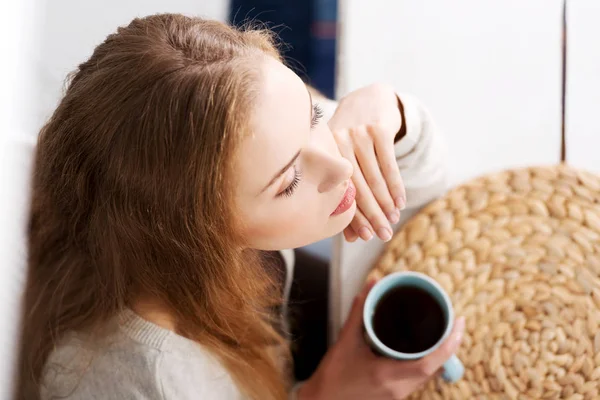 Beautiful caucasian woman is sitting by table with cup of coffee — Stock Photo, Image