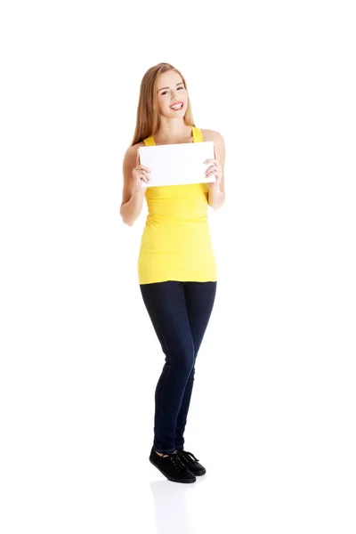 Atractiva mujer caucásica casual sostiene un pedazo de papel blanco vacío . —  Fotos de Stock