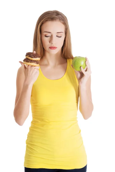 Hermosa mujer caucásica casual con donas y manzana . — Foto de Stock