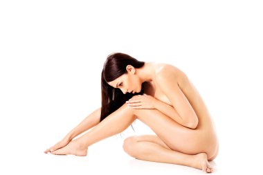 Genç çıplak kadın yerde oturuyor.