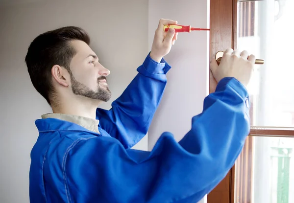 Young handyman repair window with screwdriver — Stock Photo, Image