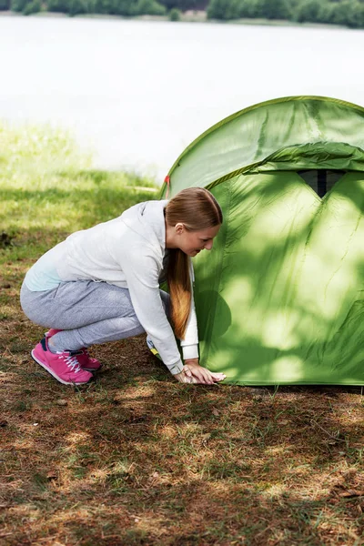 Jong blond vrouw pitching een tent. — Stockfoto