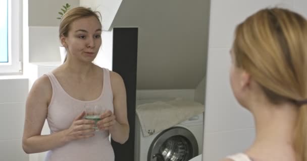 Vrouw in badkamer met mondwater vloeistof. — Stockvideo