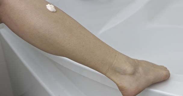 Frau im Badezimmer benutzt Lotion für ihre Beine. — Stockvideo
