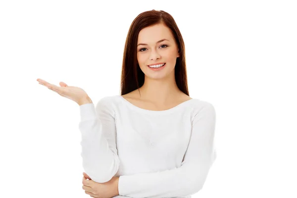 Mujer joven sonriente presentando algo en la palma abierta — Foto de Stock