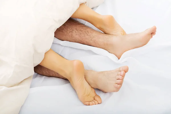 Couples feet in bed.