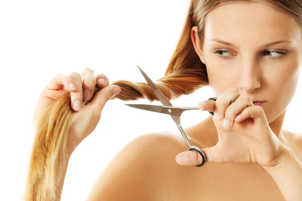 Attractive young woman is cutting her long natural hair — Stock Photo, Image