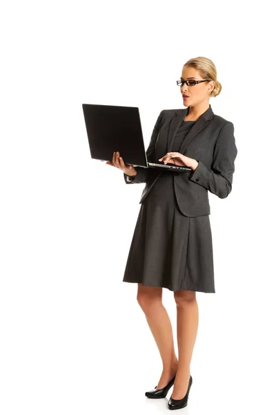 Affärskvinna ständiga och hålla en laptop — Stockfoto