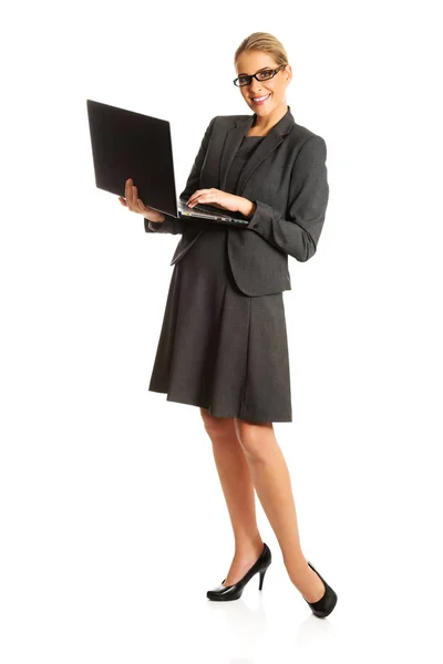 Affärskvinna ständiga och hålla en laptop — Stockfoto