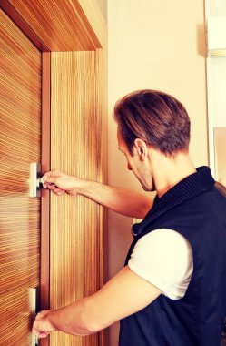 Genç adam eve dönüyor ya da evden çıkıyor.