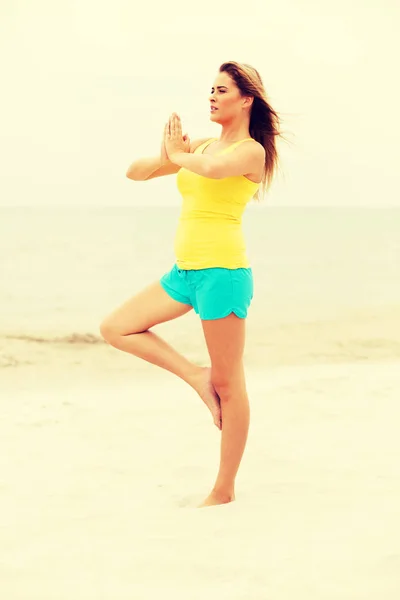 Jovem mulher fazendo exercícios de Yoga na praia — Fotografia de Stock