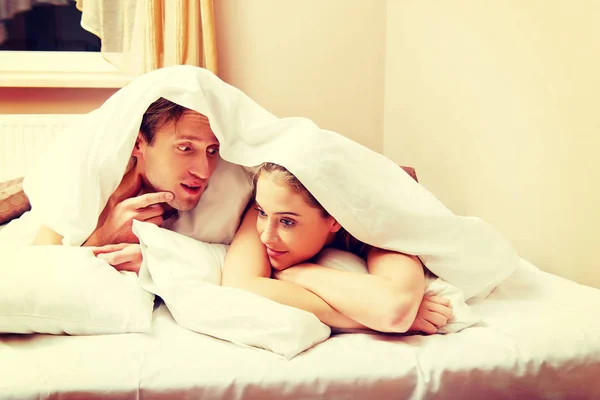 Junges Paar liegt auf Bett unter Bettdecke — Stockfoto