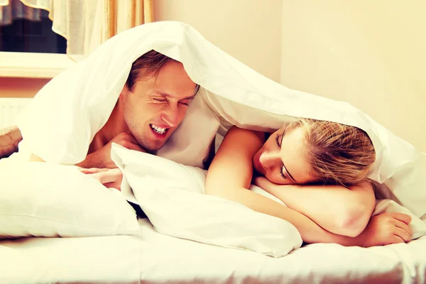 Young couple lying on bed under quilt — Stock Photo, Image