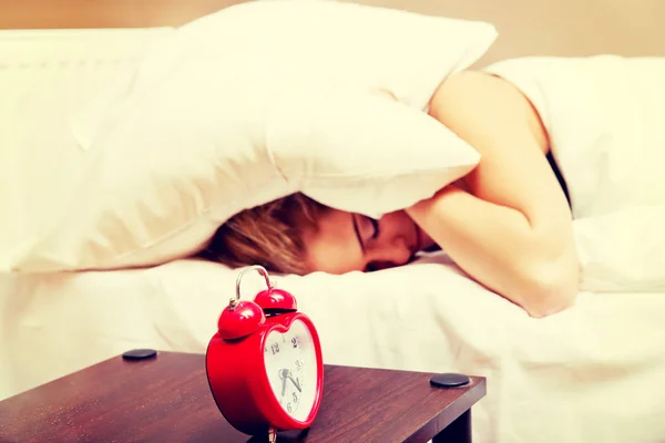 Junge Frau versucht zu schlafen, wenn der Wecker klingelt — Stockfoto
