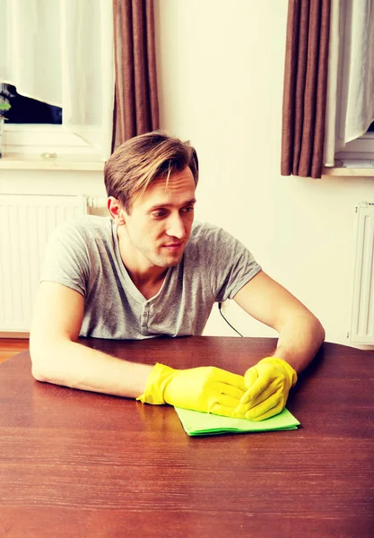 Tired man sitting behind the desk with cloth and gloves — Stock Photo, Image