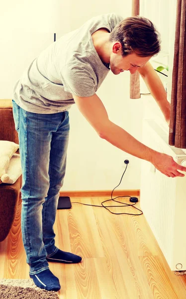 Hombre joven cambiando la temperatura del radiador — Foto de Stock