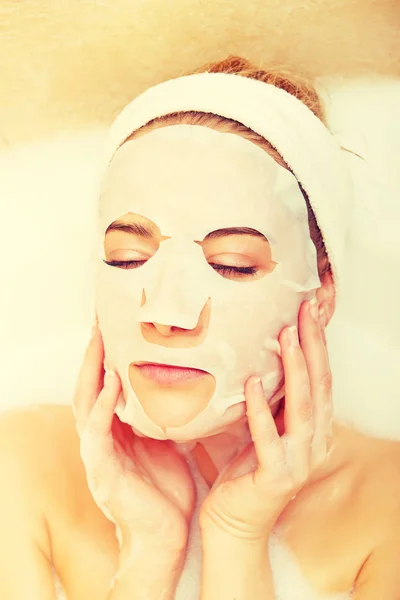 Woman sitting in bath with face mask — Stock Photo, Image