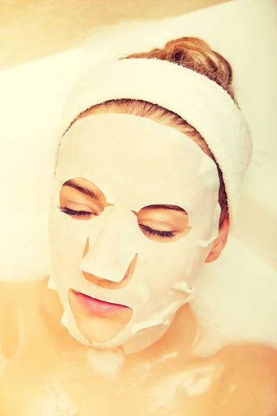 Woman sitting in bath with face mask — Stock Photo, Image