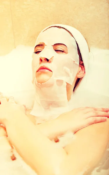 Kobieta siedzi w wannie z maską twarzy — Zdjęcie stockowe