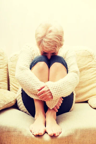Äldre kvinna med depression sittande på soffan — Stockfoto