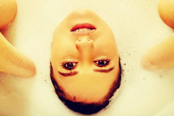 Ung kvinna som tvättar håret i badkaret — Stockfoto