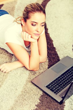 Yerde yatarken dizüstü bilgisayar kullanan genç kadın odaklı 