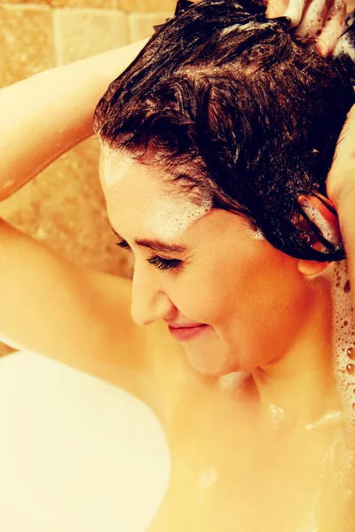 Молодая счастливая женщина моет волосы в ванной — стоковое фото