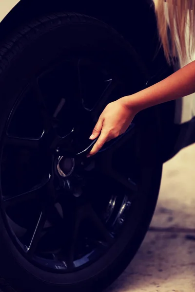 Mulher está mudando pneu do carro com chave de rodas — Fotografia de Stock