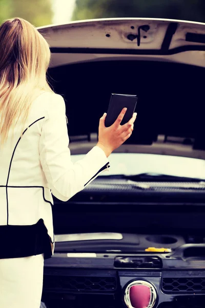 Woman peeks under the open hood — Stock Photo, Image