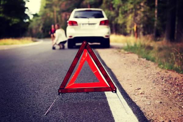 Triángulo rojo de advertencia y coche roto en medio del bosque —  Fotos de Stock