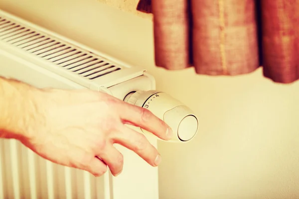 Jovem homem mudando a temperatura do radiador — Fotografia de Stock