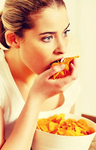 Giovane donna guardando la TV e mangiare patatine fritte — Foto Stock