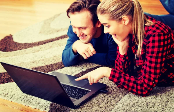 Gelukkig paar liggend op de vloer met laptop — Stockfoto