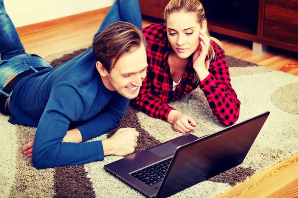 Casal feliz deitado no chão com laptop — Fotografia de Stock