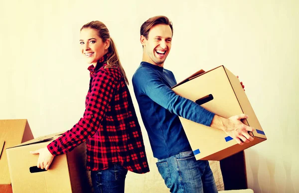 Pareja feliz llevando cajas de cartón en un nuevo hogar — Foto de Stock
