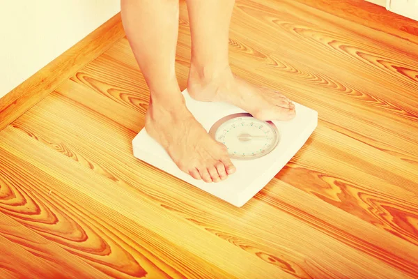 Mulher sênior em pé na balança de peso na sala de estar — Fotografia de Stock