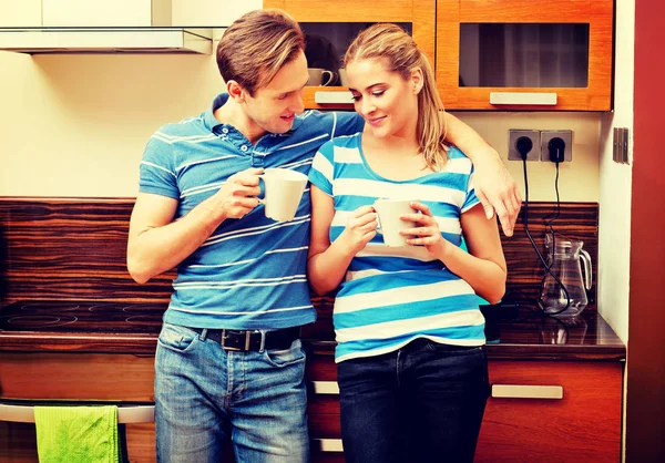 Young couple drinking coffee or tea in kitchen — Stock Photo, Image