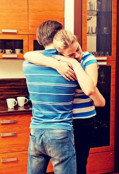 Счастливая молодая пара обнимается на кухне — стоковое фото