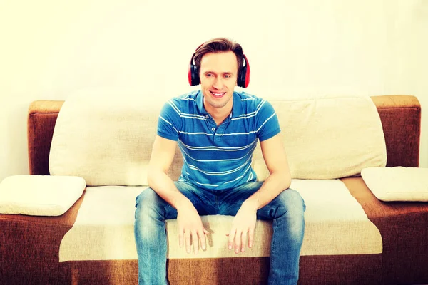 Happy man sitting on sofa and listening music — Stock Photo, Image