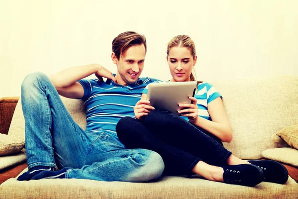 Giovane coppia seduta a casa e in cerca di qualcosa su tablet — Foto Stock