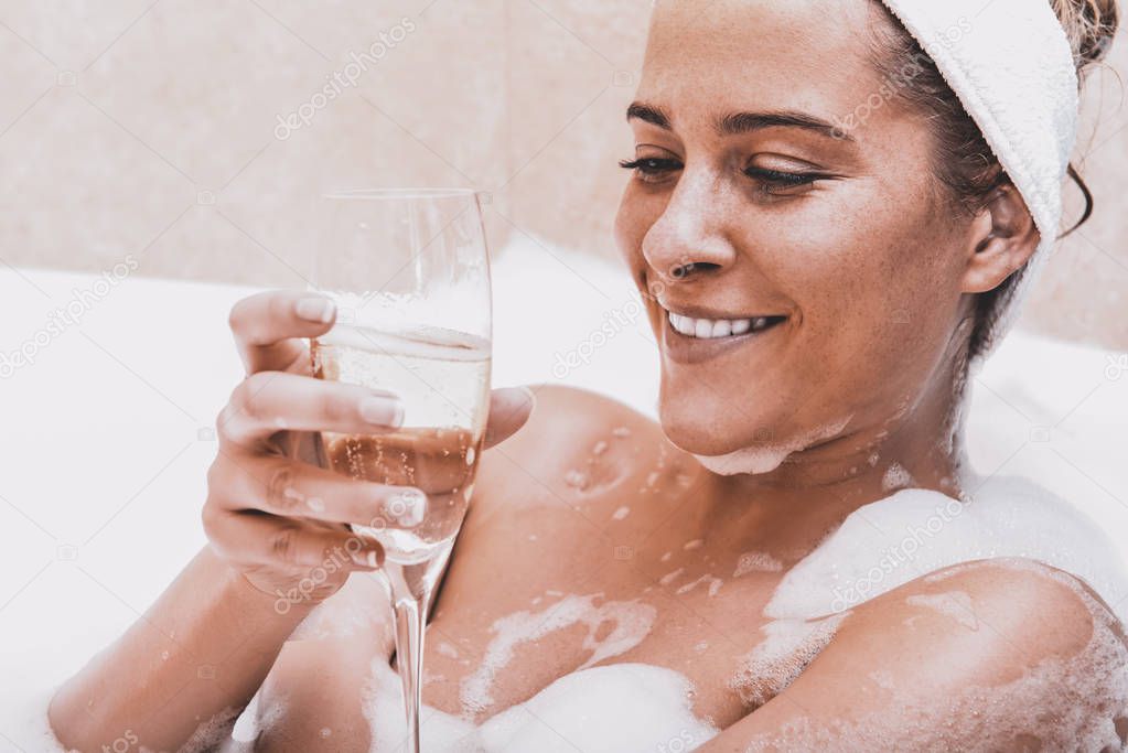 Woman in bath with champagne
