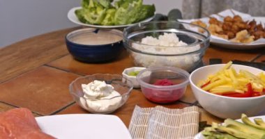 Hazırlanıyor, suşi yuvarlanıyor. Somon, avokado, yosun üzerinde pirinç ve ahşap masada yemek çubukları.