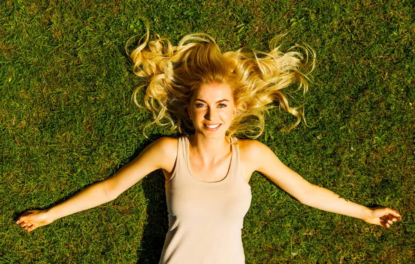 Lachende blonde vrouw op gras — Stockfoto