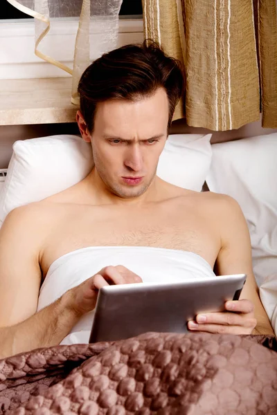 Mann mit Tablette im Bett — Stockfoto