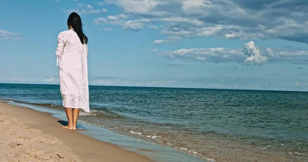 Женщина стоит на пустом пляже — стоковое фото