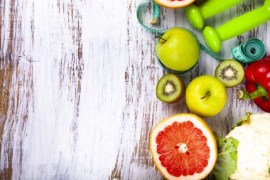 Gıda diyet ve ahşap arka plan üzerinde halter. Diyet ve sağlıklı yaşam kavramı.