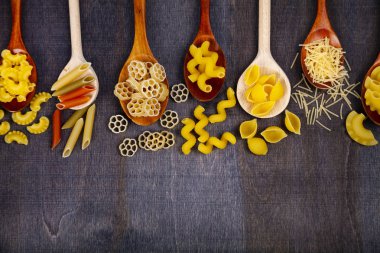 Kaşık koyu ahşap arka plan, üstten görünüm üzerinde farklı makarna. 