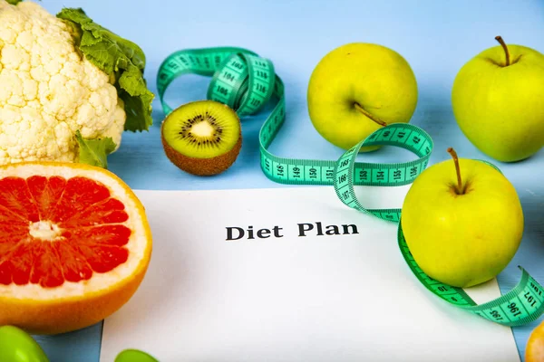 Food and sheet of paper with a diet plan on a blue wooden background. Concept of diet and healthy lifestyle.