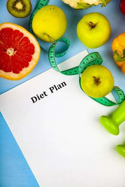 Food and sheet of paper with a diet plan on a blue wooden background. Concept of diet and healthy lifestyle.