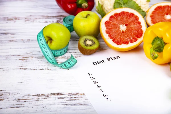 Food and sheet of paper with a diet plan on a wooden background. Concept of diet and healthy lifestyle.